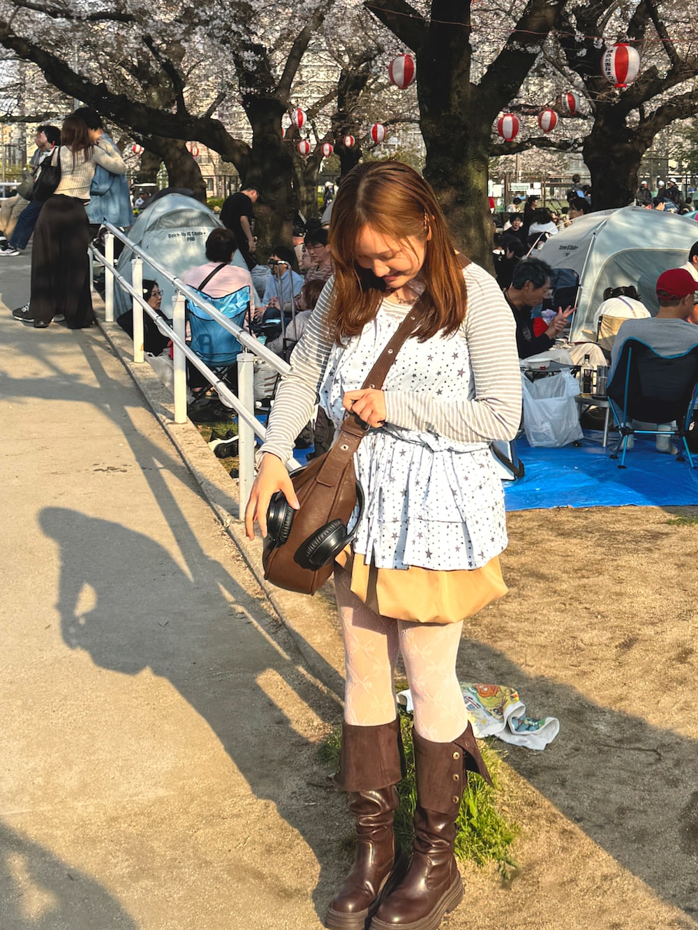 ブルー系のキャミソール、グレー系のトップス、ベージュ系のスカートを着用したレディースの春コーディネートの2枚目の写真