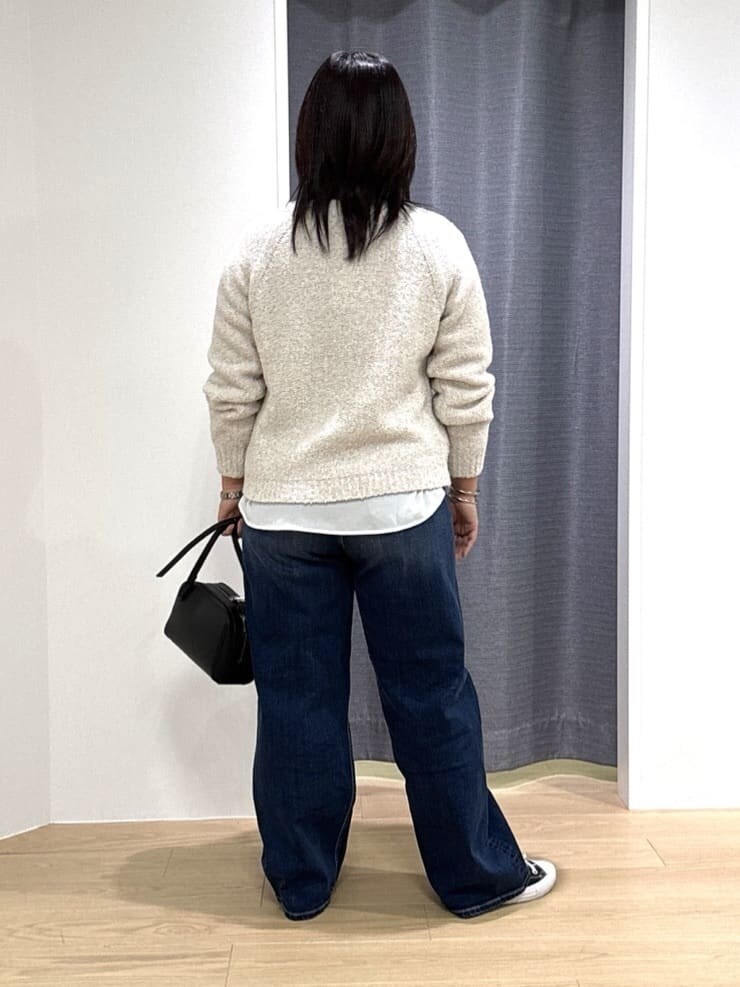 ホワイト系のショルダーバッグ、ホワイト系のニット/セーター、ブルー系のデニムパンツを着用したレディースの冬コーディネートの4枚目の写真
