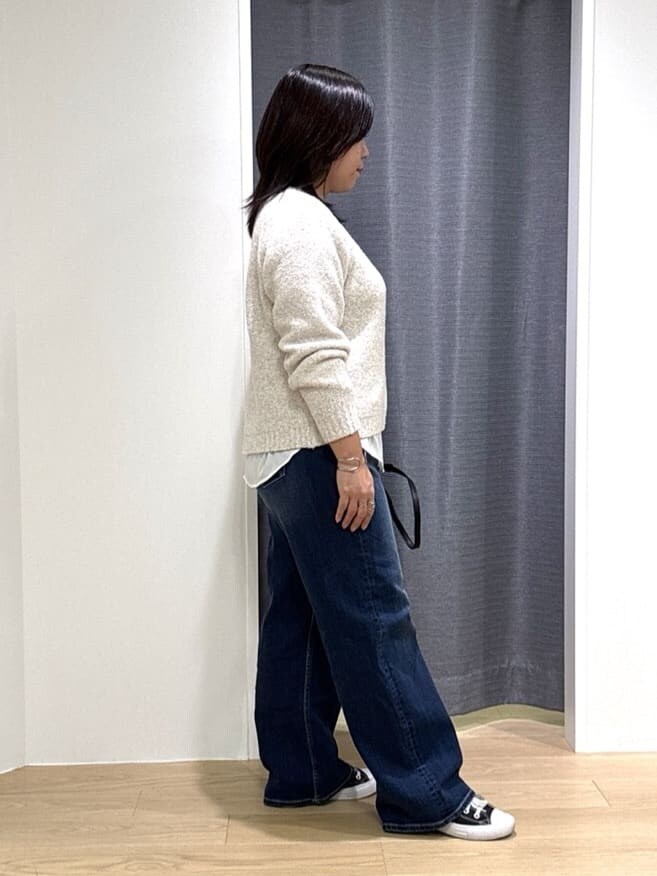 ホワイト系のショルダーバッグ、ホワイト系のニット/セーター、ブルー系のデニムパンツを着用したレディースの冬コーディネートの5枚目の写真
