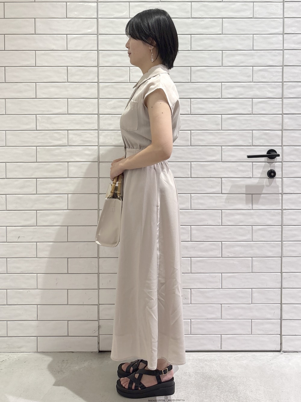 ベージュ系のワンピース、ホワイト系のトートバッグ、ブラック系のサンダルを着用したレディースの夏コーディネートの2枚目の写真