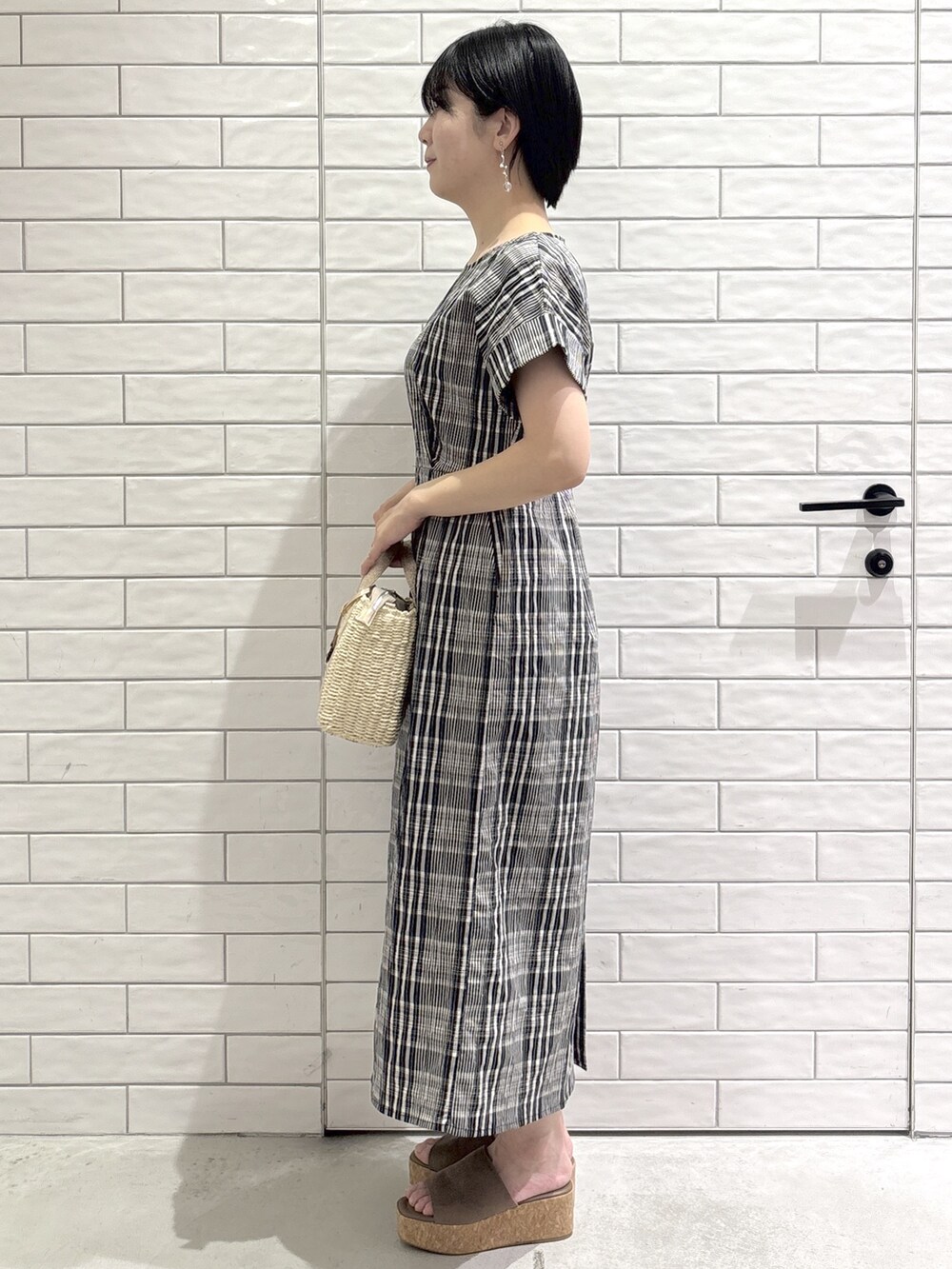ブラック系のワンピース、ベージュ系のトートバッグ、ベージュ系のサンダルを着用したレディースの春コーディネートの2枚目の写真