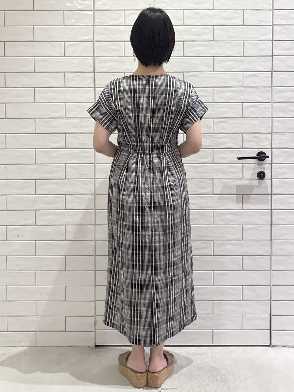 ブラック系のワンピース、ベージュ系のトートバッグ、ベージュ系のサンダルを着用したレディースの春コーディネートの3枚目の写真