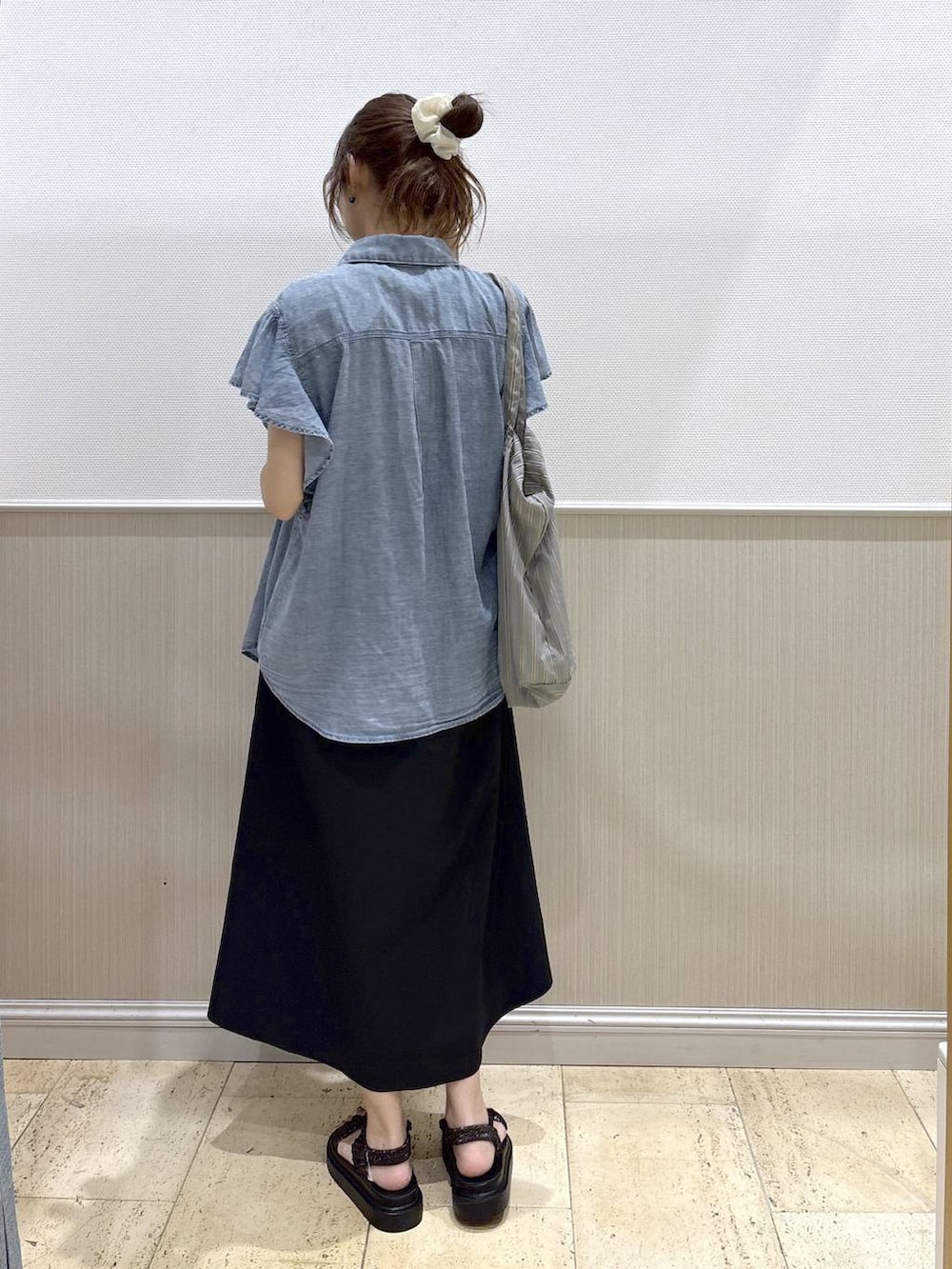 グレー系のトートバッグ、ブラック系のワンピース、ブラック系のサンダルを着用したレディースの夏コーディネートの5枚目の写真