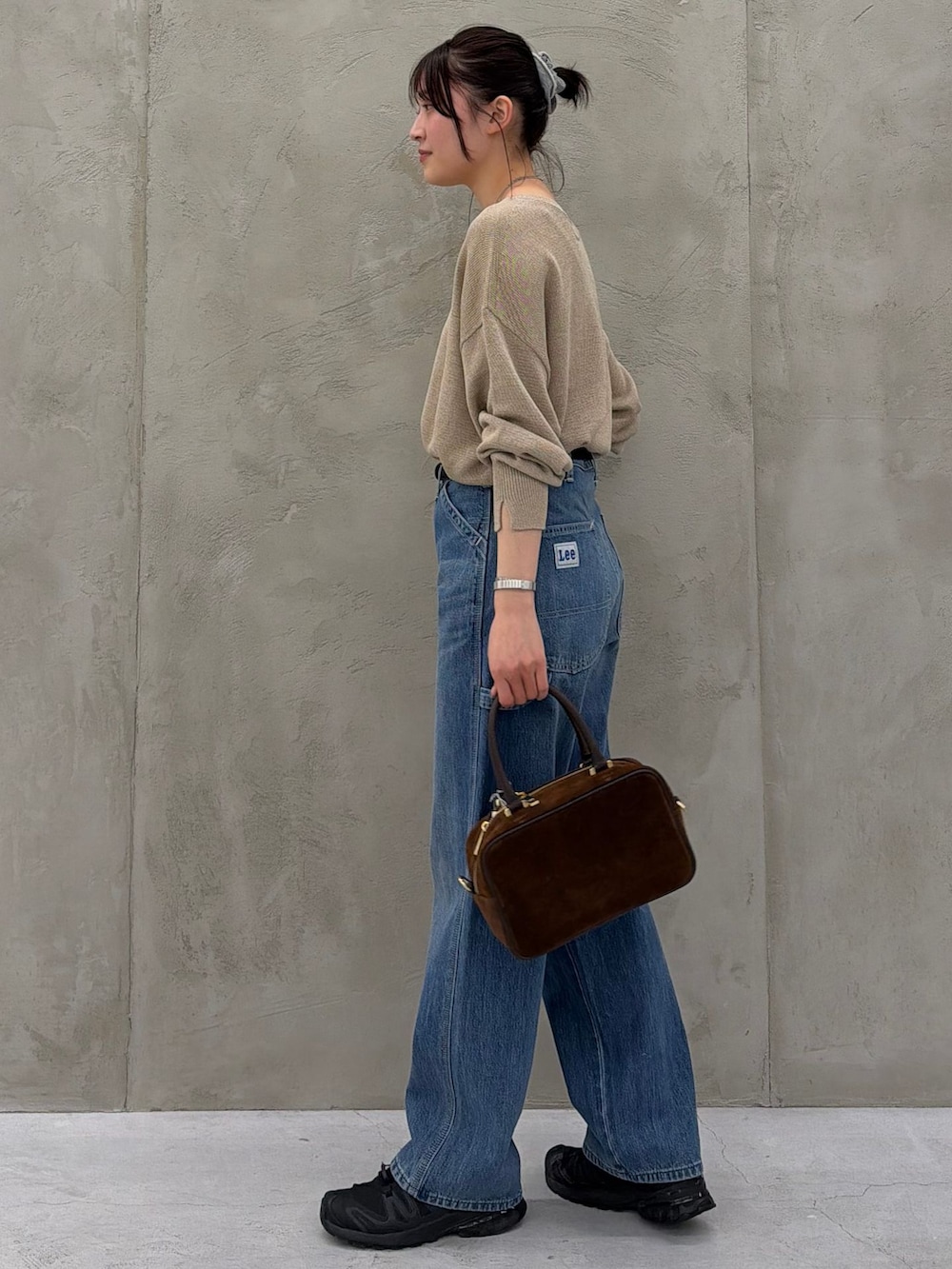 ブルー系のデニムパンツ、ベージュ系のニット/セーター、ブラウン系のショルダーバッグを着用したレディースの春コーディネートの7枚目の写真