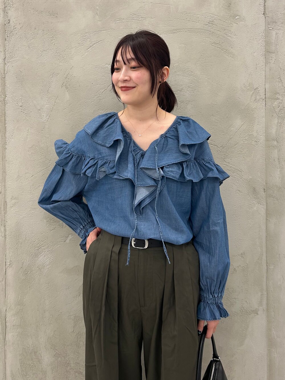 グリーン系のチノパンツ、ブルー系のシャツ/ブラウス、ブラック系のショルダーバッグを着用したレディースの冬コーディネートの9枚目の写真