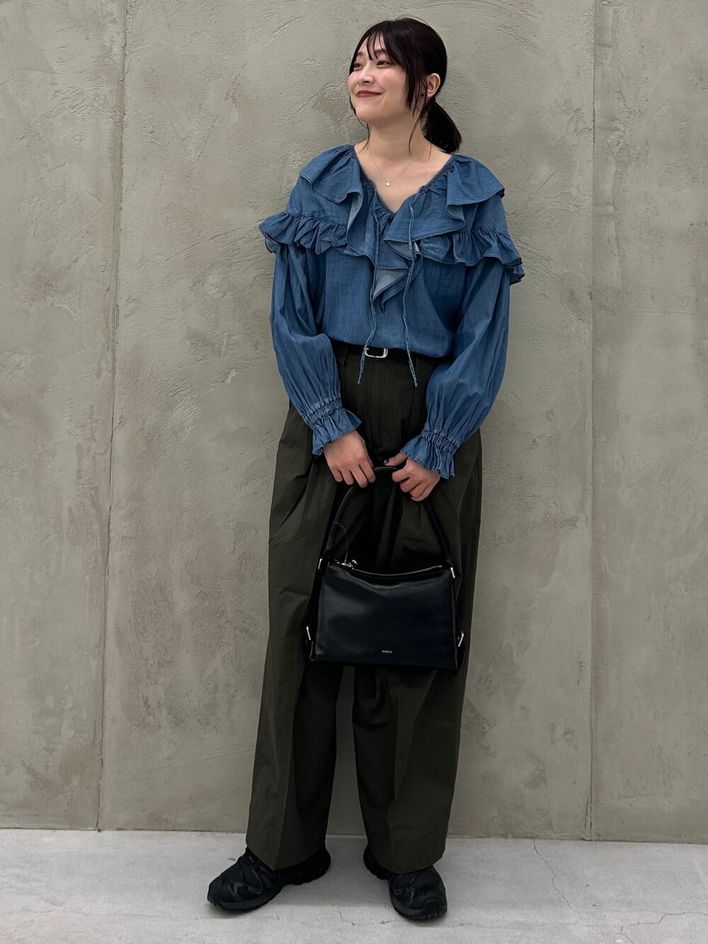 グリーン系のチノパンツ、ブルー系のシャツ/ブラウス、ブラック系のショルダーバッグを着用したレディースの冬コーディネートの7枚目の写真