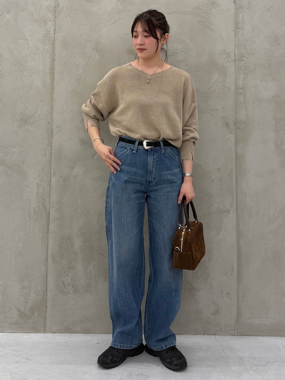 ブルー系のデニムパンツ、ベージュ系のニット/セーター、ブラウン系のショルダーバッグを着用したレディースの春コーディネートの3枚目の写真