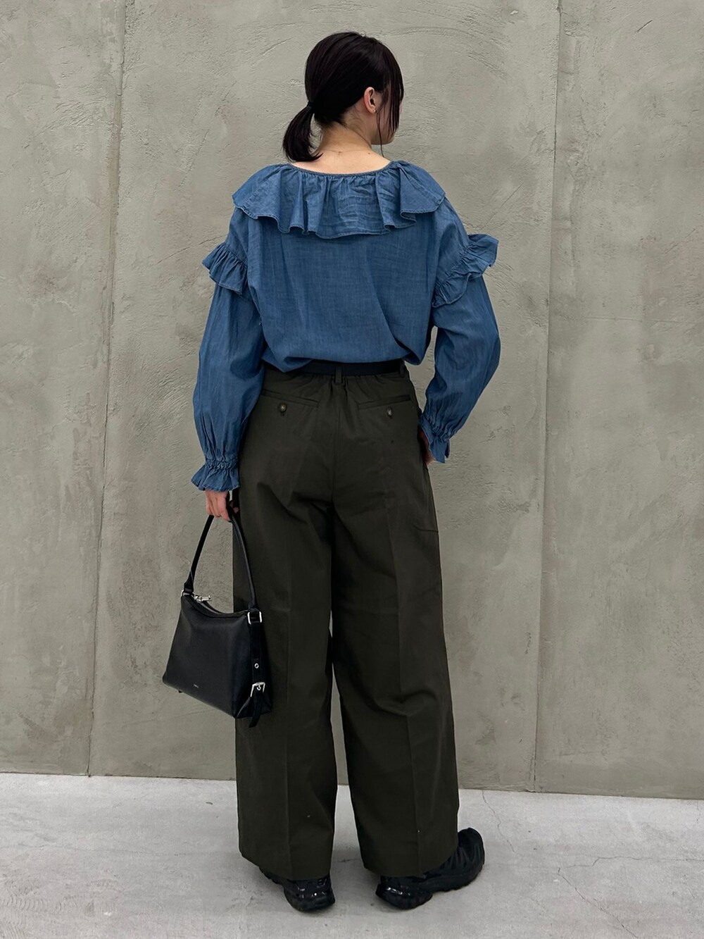 グリーン系のチノパンツ、ブルー系のシャツ/ブラウス、ブラック系のショルダーバッグを着用したレディースの冬コーディネートの5枚目の写真