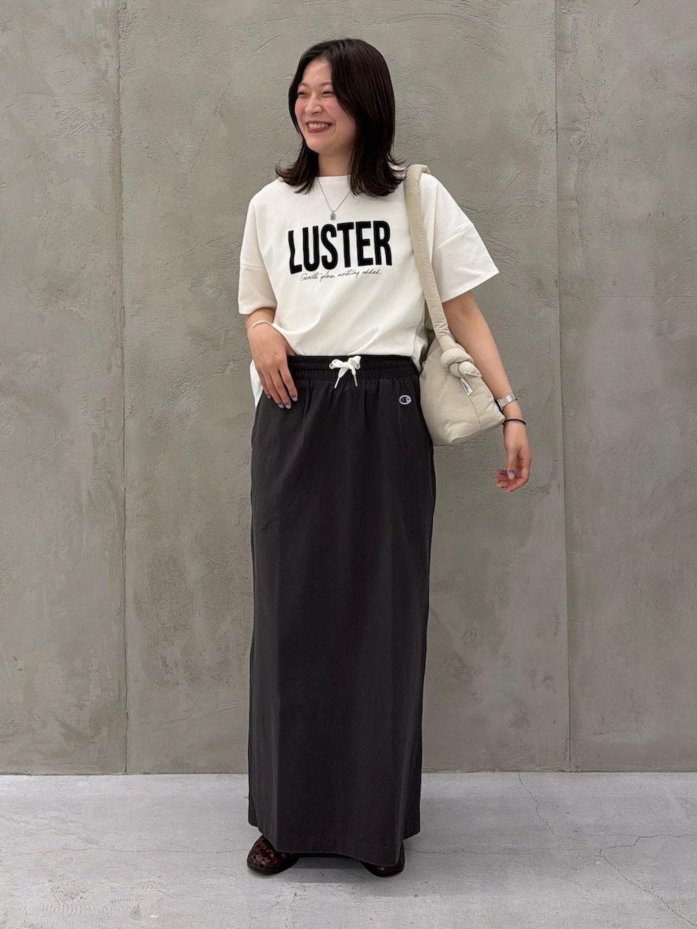 ブラック系のスカート、ホワイト系のTシャツ/カットソー、ベージュ系のショルダーバッグを着用したレディースの春コーディネートの2枚目の写真