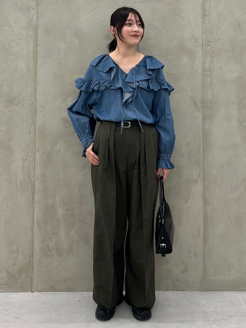 グリーン系のチノパンツ、ブルー系のシャツ/ブラウス、ブラック系のショルダーバッグを着用したレディースの冬コーディネートの2枚目の写真