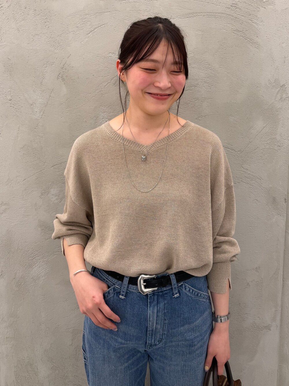 ブルー系のデニムパンツ、ベージュ系のニット/セーター、ブラウン系のショルダーバッグを着用したレディースの春コーディネートの9枚目の写真