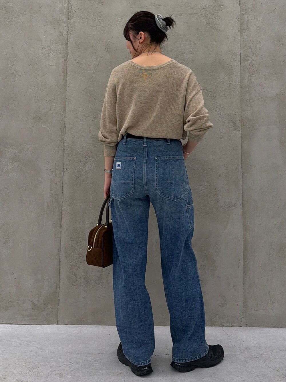 ブルー系のデニムパンツ、ベージュ系のニット/セーター、ブラウン系のショルダーバッグを着用したレディースの春コーディネートの6枚目の写真