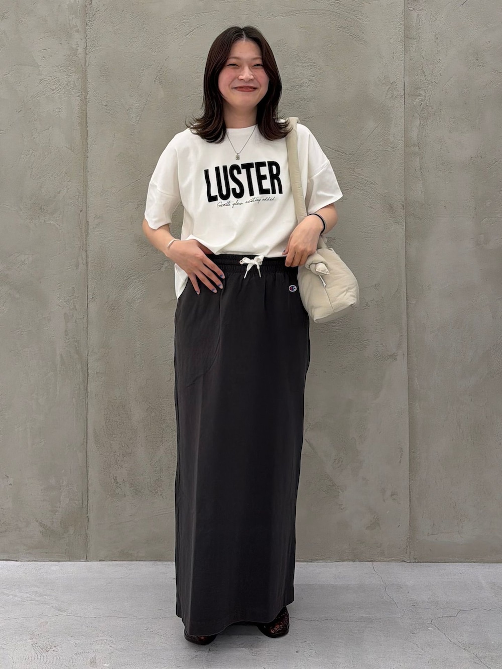ブラック系のスカート、ホワイト系のTシャツ/カットソー、ベージュ系のショルダーバッグを着用したレディースの春コーディネートの7枚目の写真