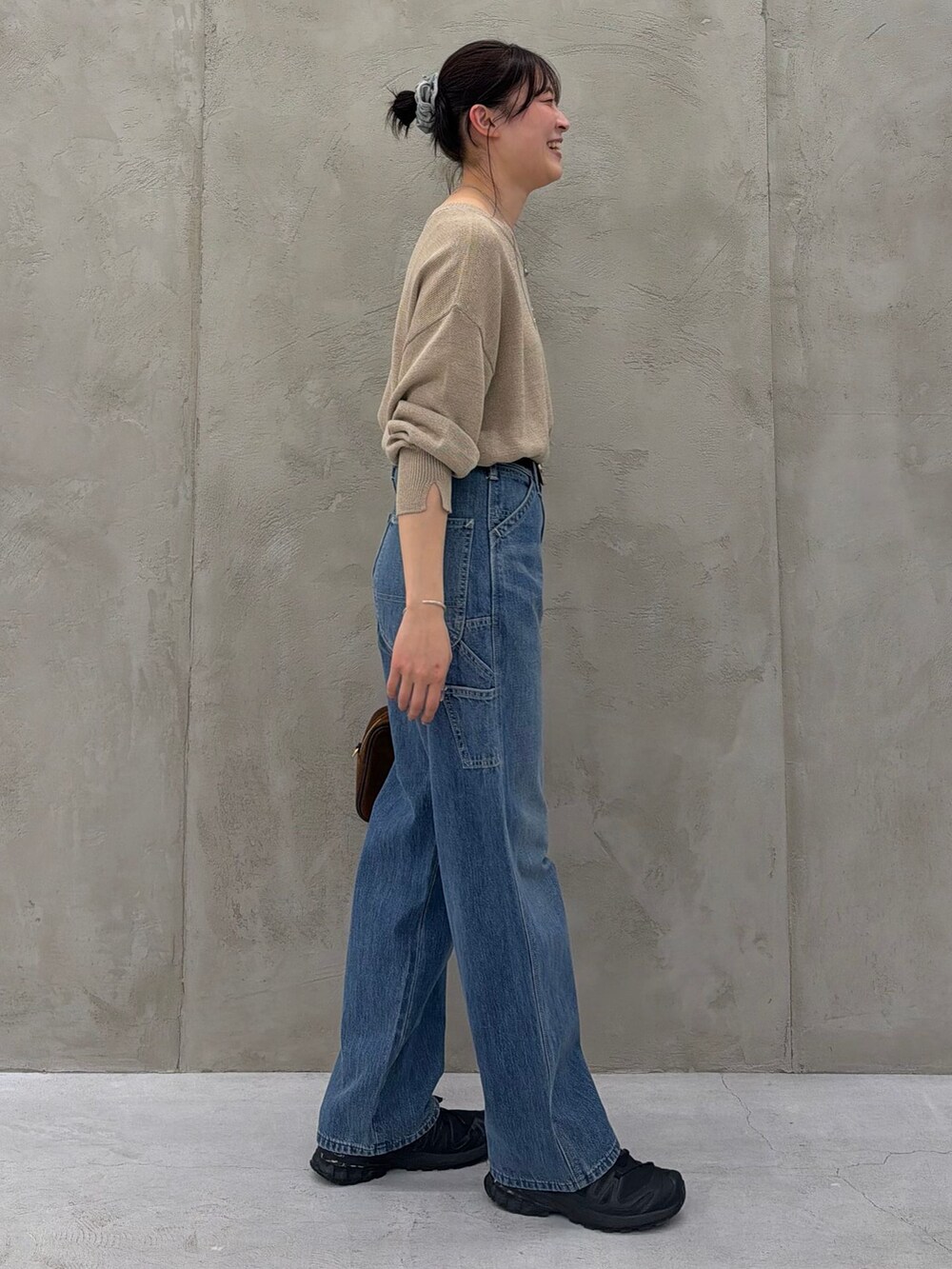 ブルー系のデニムパンツ、ベージュ系のニット/セーター、ブラウン系のショルダーバッグを着用したレディースの春コーディネートの4枚目の写真