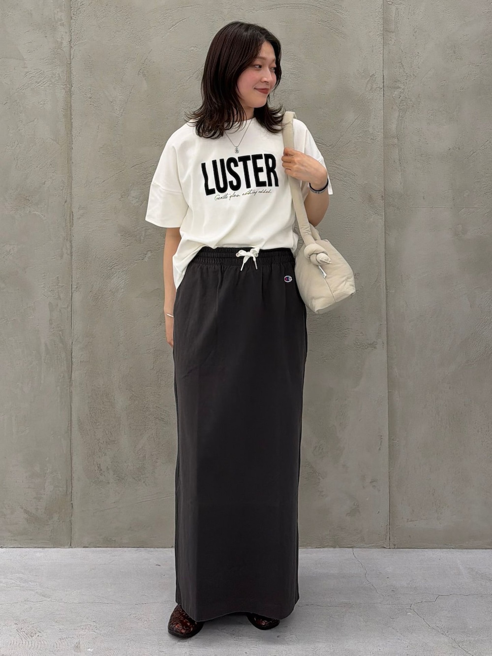 ブラック系のスカート、ホワイト系のTシャツ/カットソー、ベージュ系のショルダーバッグを着用したレディースの春コーディネートの3枚目の写真
