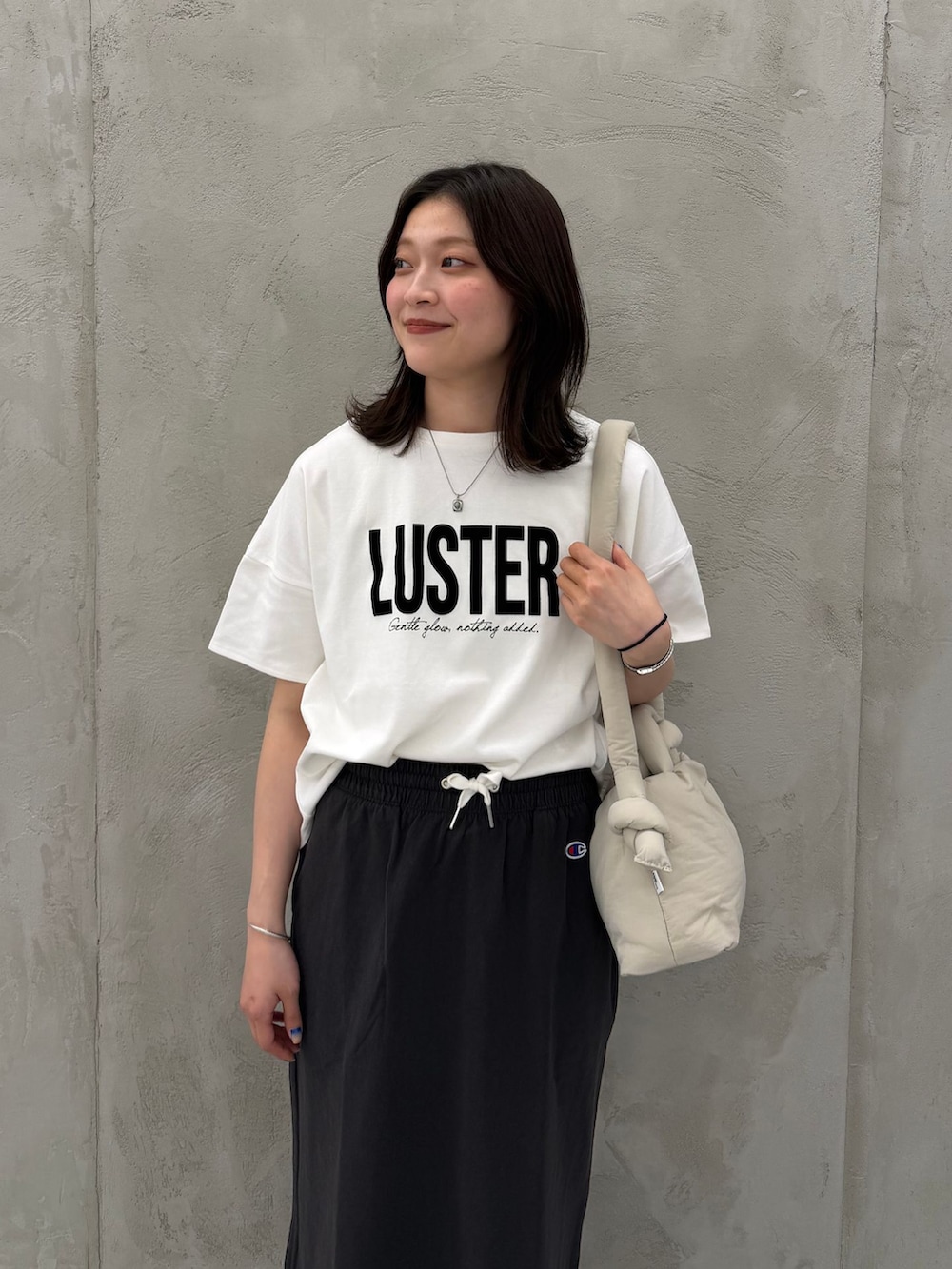 ブラック系のスカート、ホワイト系のTシャツ/カットソー、ベージュ系のショルダーバッグを着用したレディースの春コーディネートの9枚目の写真