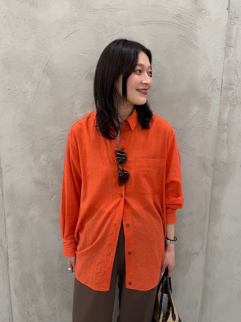 ブラウン系のその他パンツ、オレンジ系のシャツ/ブラウス、グリーン系のかごバッグを着用したレディースの夏コーディネートの9枚目の写真