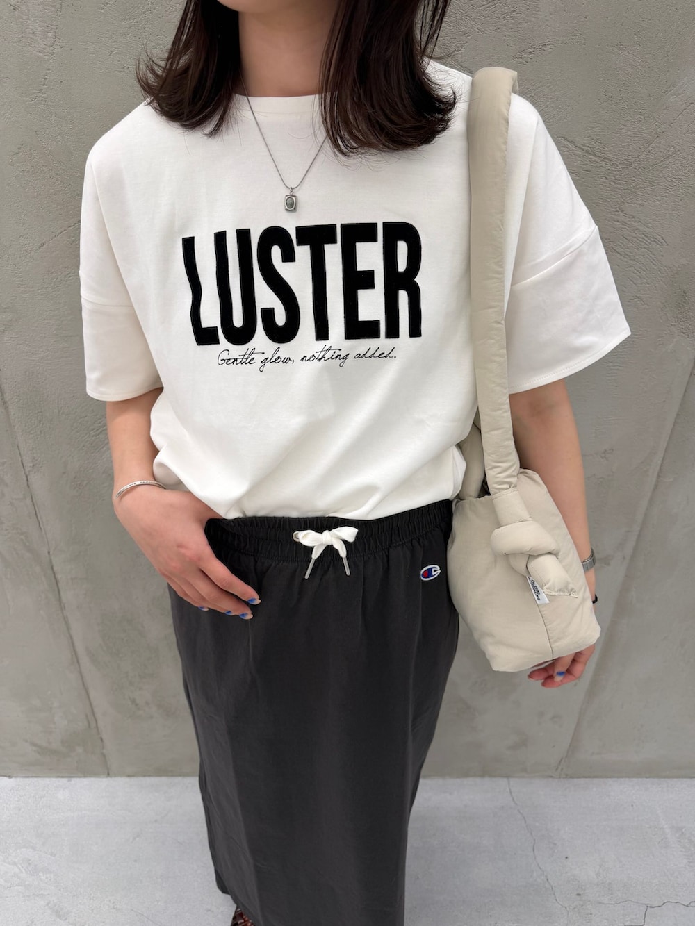 ブラック系のスカート、ホワイト系のTシャツ/カットソー、ベージュ系のショルダーバッグを着用したレディースの春コーディネートの10枚目の写真