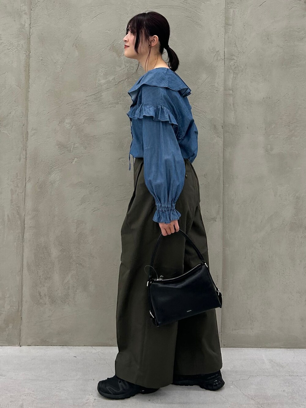 グリーン系のチノパンツ、ブルー系のシャツ/ブラウス、ブラック系のショルダーバッグを着用したレディースの冬コーディネートの4枚目の写真
