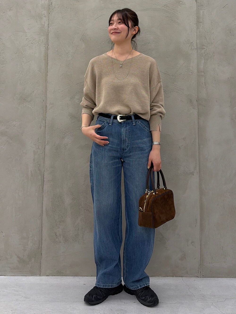 ブルー系のデニムパンツ、ベージュ系のニット/セーター、ブラウン系のショルダーバッグを着用したレディースの春コーディネートの2枚目の写真