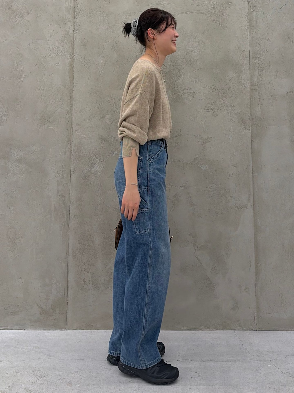ブルー系のデニムパンツ、ベージュ系のニット/セーター、ブラウン系のショルダーバッグを着用したレディースの春コーディネートの5枚目の写真