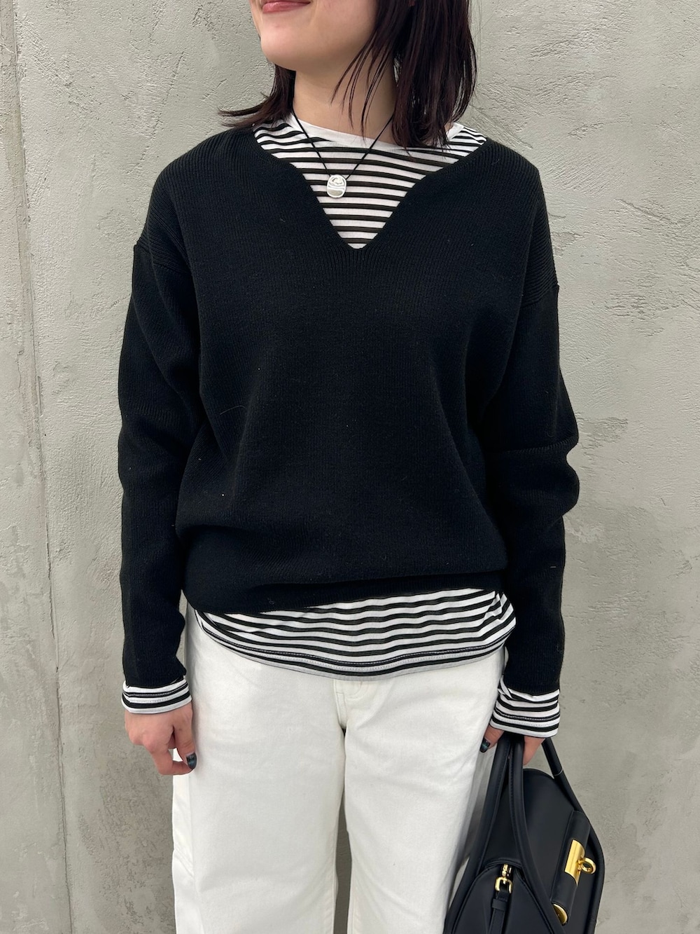ホワイト系のデニムパンツ、ブラック系のTシャツ/カットソー、ブラック系のニット/セーターを着用したレディースの冬コーディネートの8枚目の写真