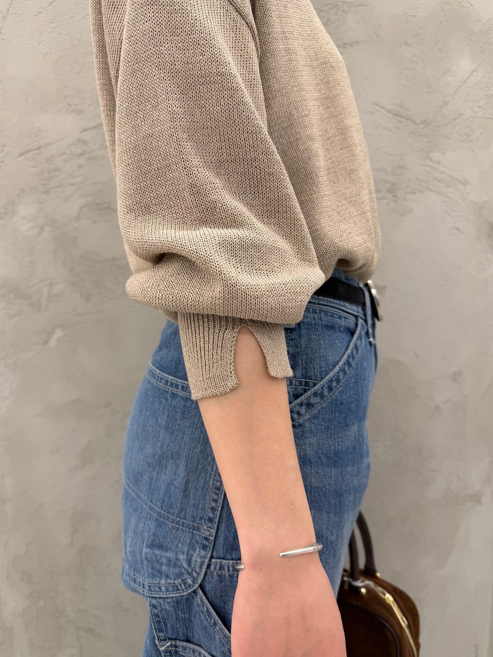 ブルー系のデニムパンツ、ベージュ系のニット/セーター、ブラウン系のショルダーバッグを着用したレディースの春コーディネートの10枚目の写真