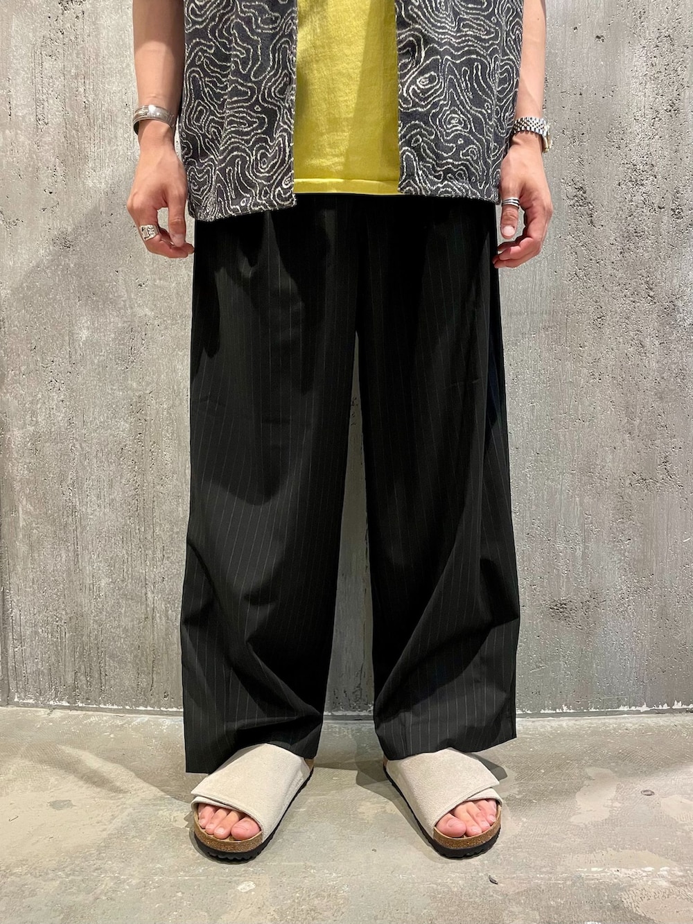 ブラック系のスラックス、ブラック系のシャツ/ブラウス、イエロー系のTシャツ/カットソーを着用したメンズの夏コーディネートの3枚目の写真