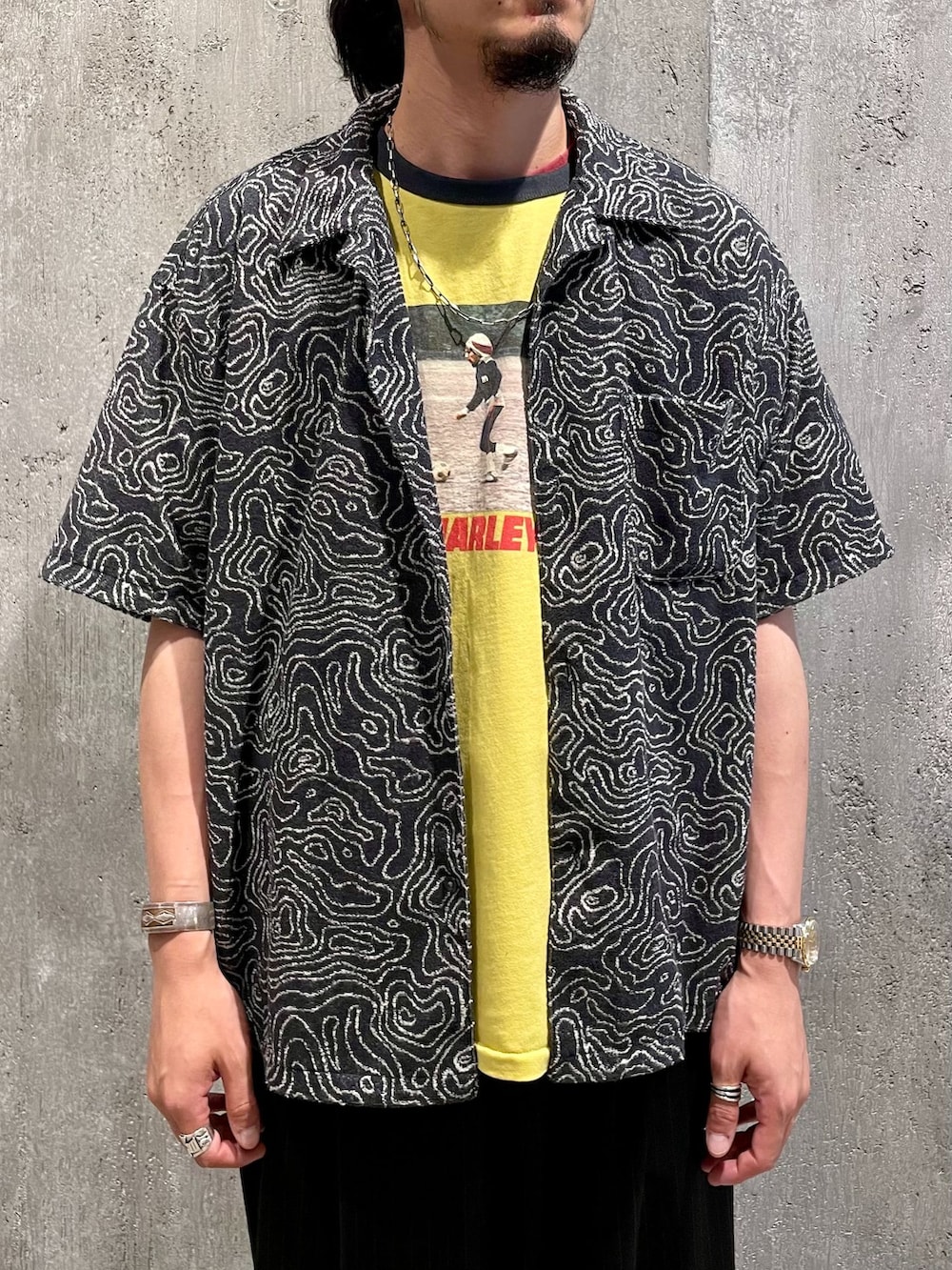 ブラック系のスラックス、ブラック系のシャツ/ブラウス、イエロー系のTシャツ/カットソーを着用したメンズの夏コーディネートの2枚目の写真