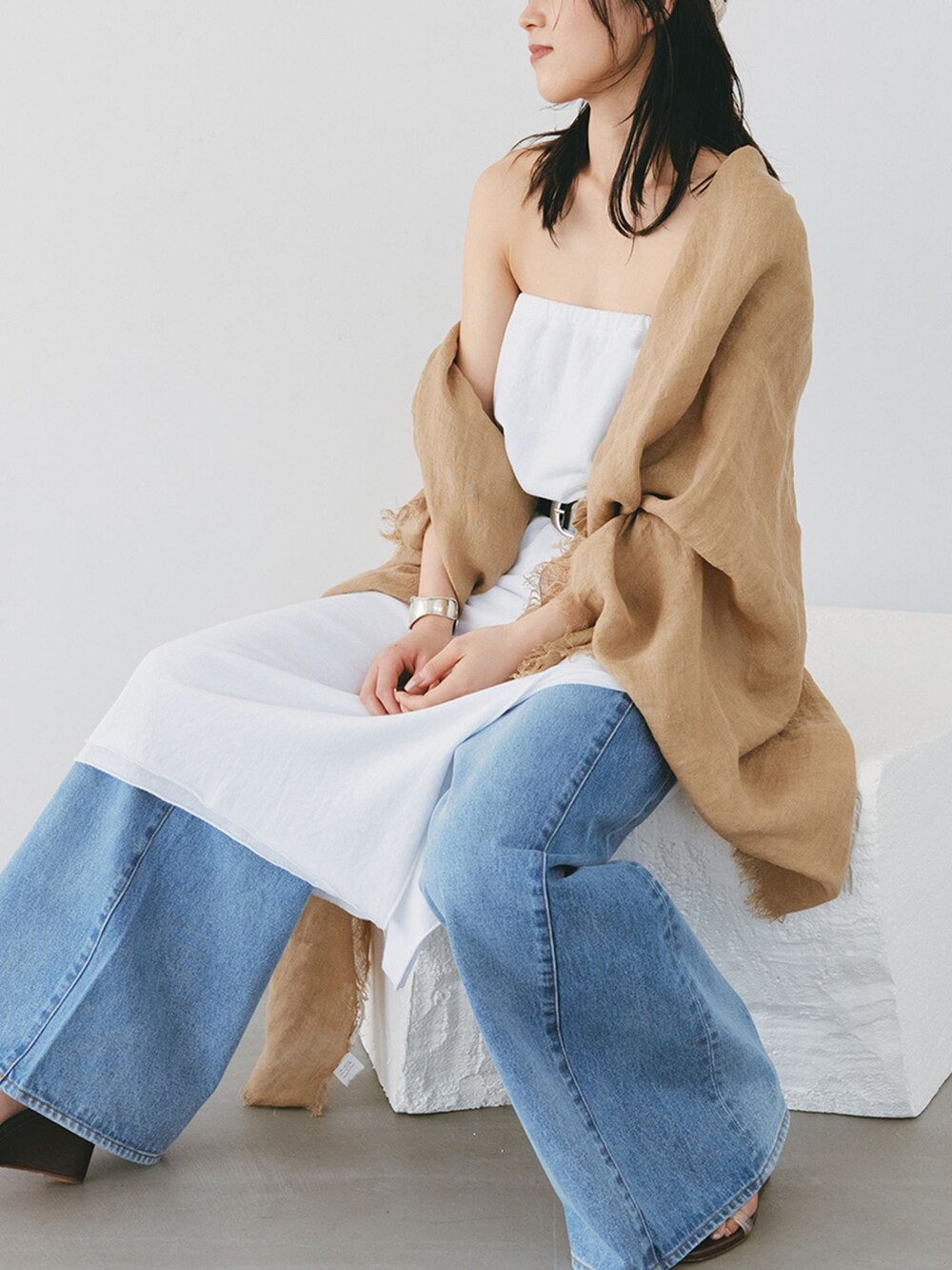 ブルー系のデニムパンツ、ホワイト系のスカート、ブラック系のベルトを着用したレディースの夏コーディネートの3枚目の写真
