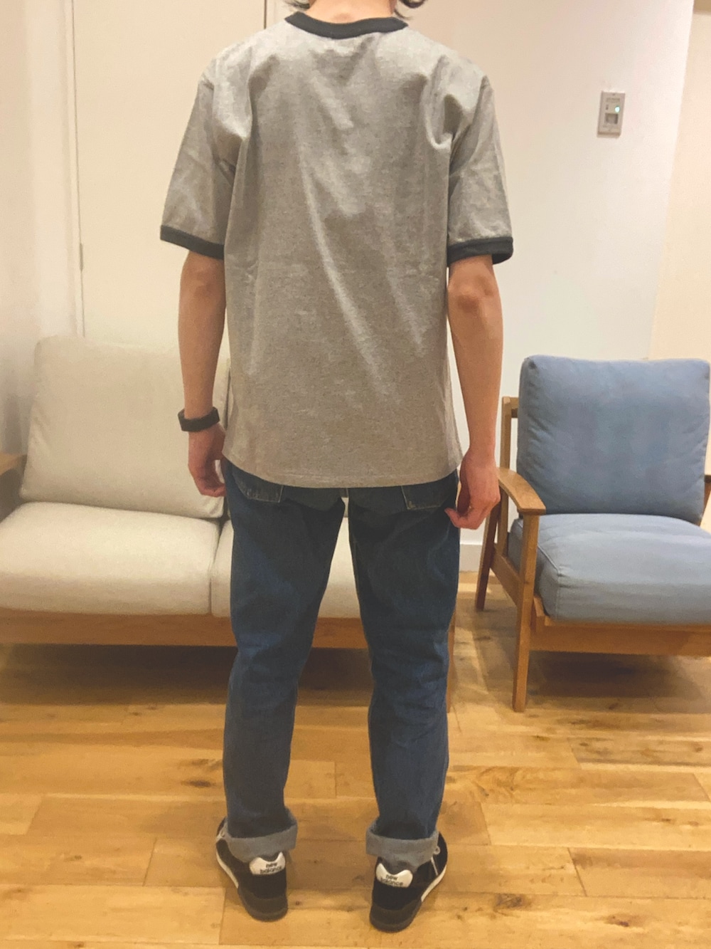 ブルー系のデニムパンツ、ブラック系のスニーカー、グレー系のTシャツ/カットソーを着用したメンズの春コーディネートの2枚目の写真