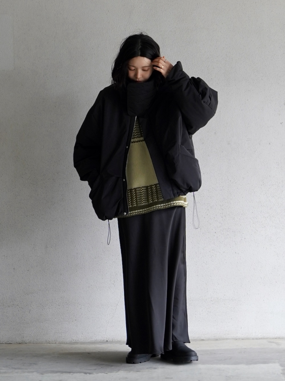 ブラック系のスカート、ブラック系のダウンジャケット/コート、ブラック系のブーツを着用したレディースの冬コーディネートの2枚目の写真