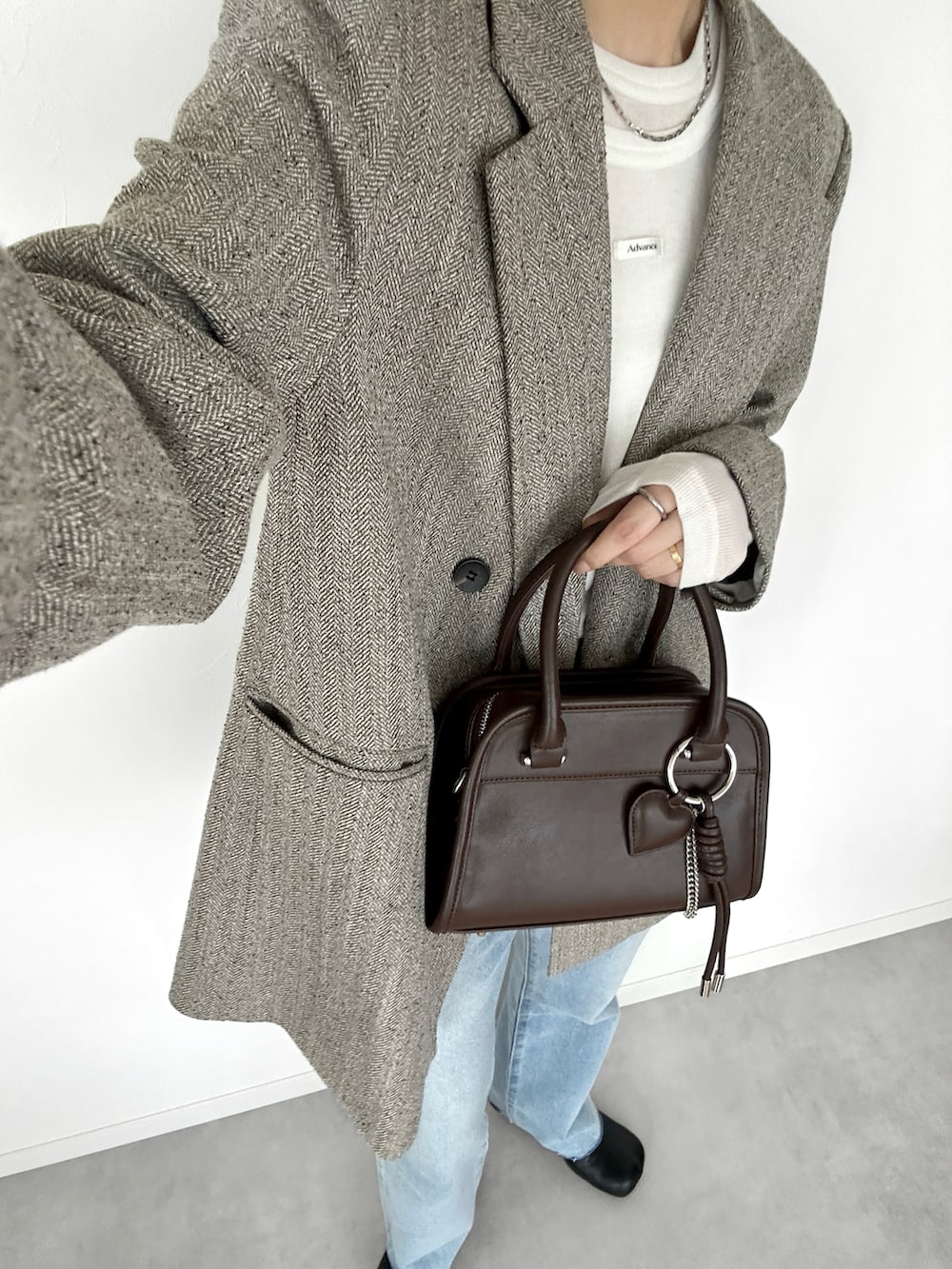 ホワイト系のTシャツ/カットソー、ブラウン系のボストンバッグ、ブラック系のブーツを着用したレディースの秋コーディネートの3枚目の写真