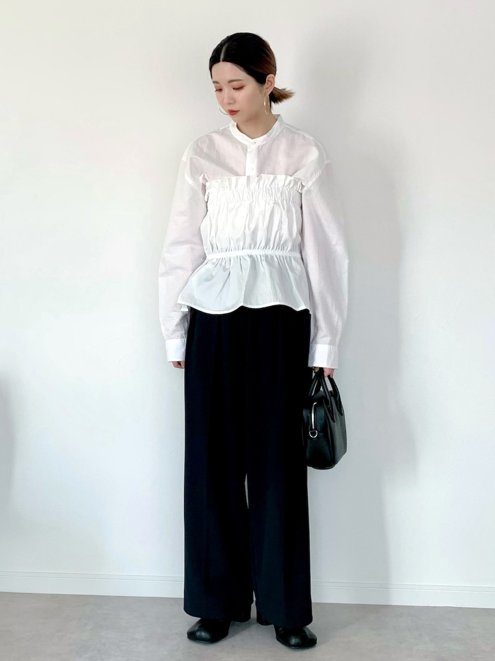 ホワイト系のベスト、ブラック系のその他パンツ、ブラック系のハンドバッグを着用したレディースの冬コーディネートの2枚目の写真