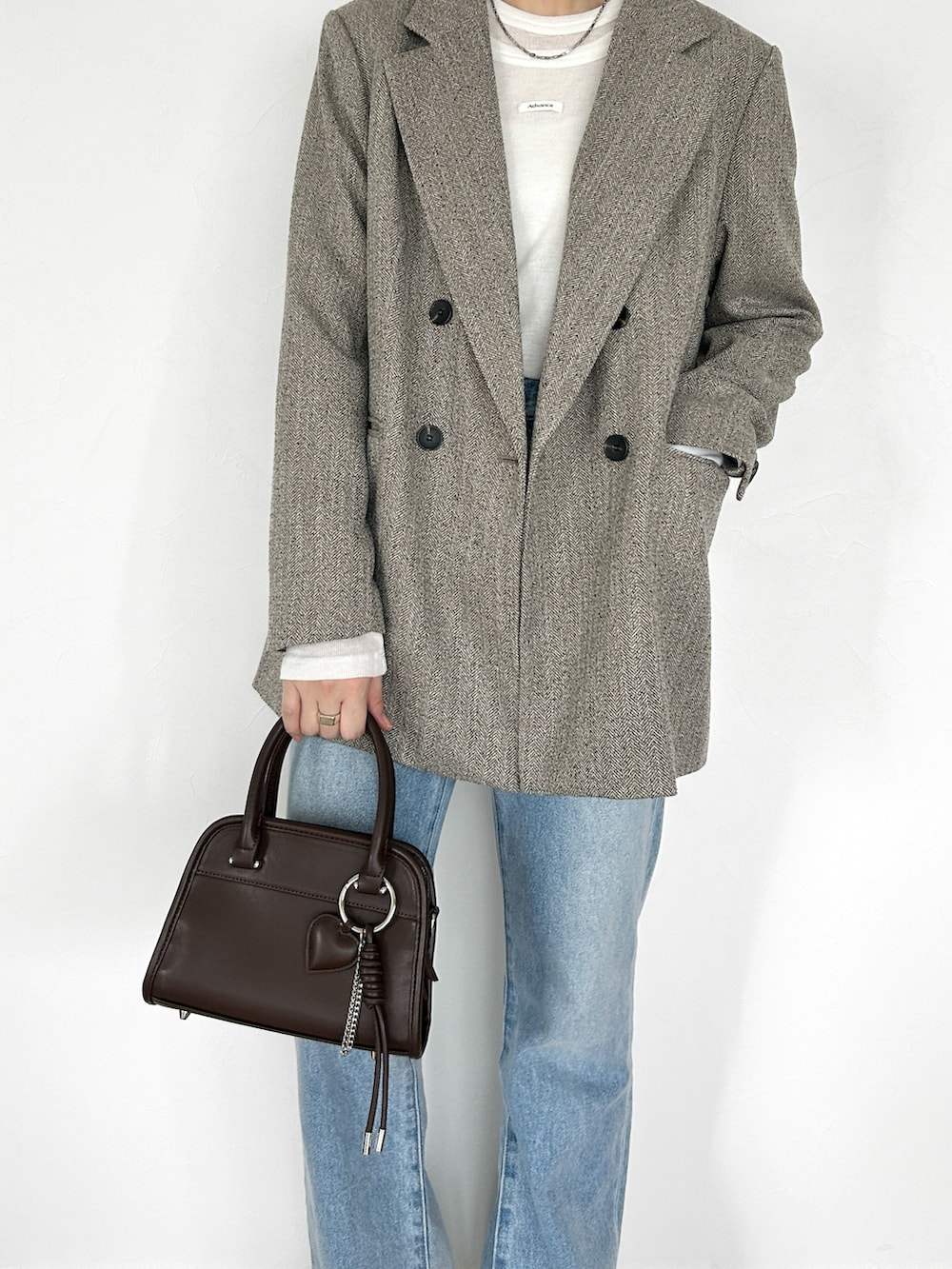 ホワイト系のTシャツ/カットソー、ブラウン系のボストンバッグ、ブラック系のブーツを着用したレディースの秋コーディネートの2枚目の写真