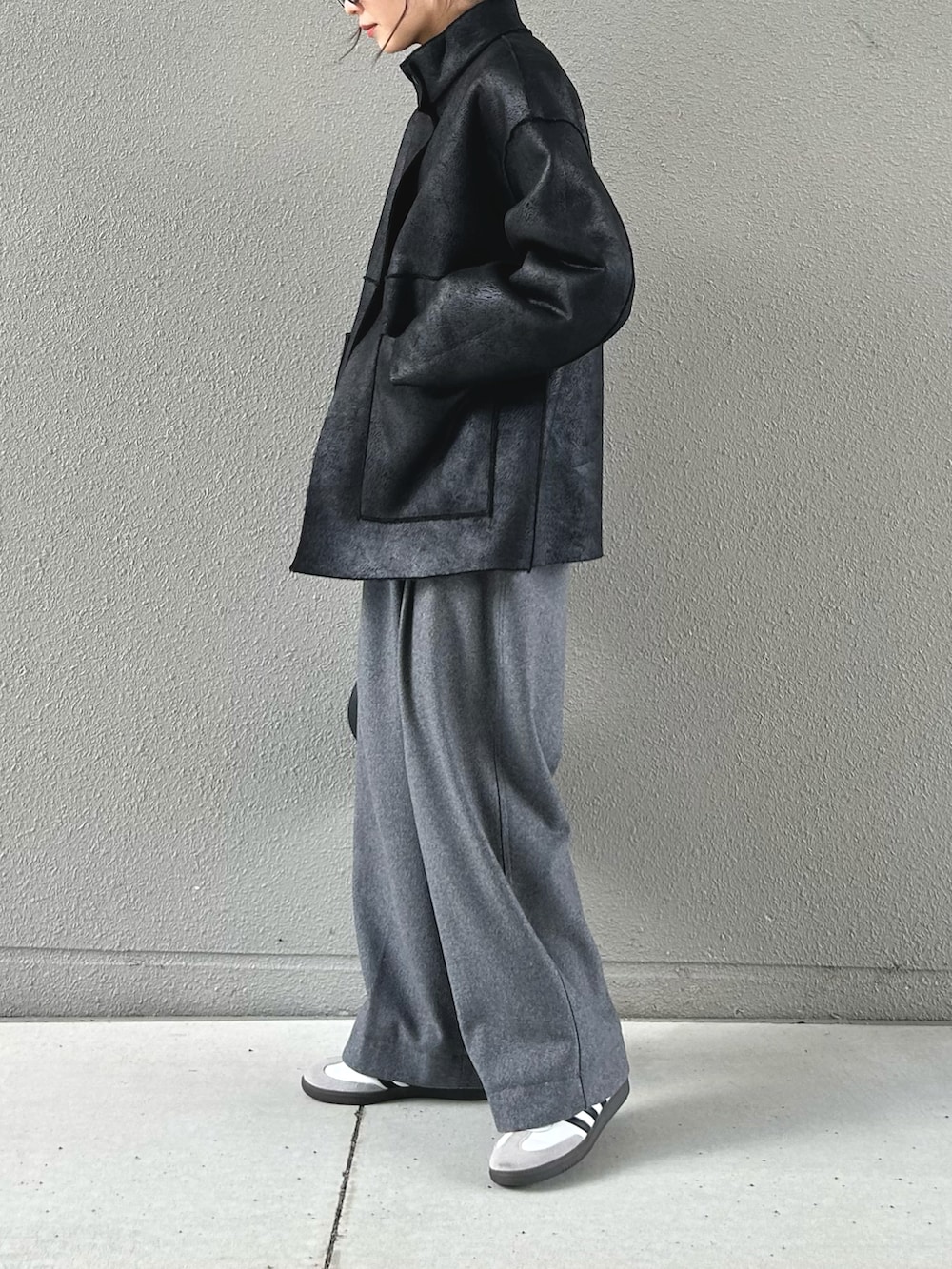 ブラック系のムートンコート、グレー系のスラックス、ホワイト系のスニーカーを着用したレディースの冬コーディネートの2枚目の写真