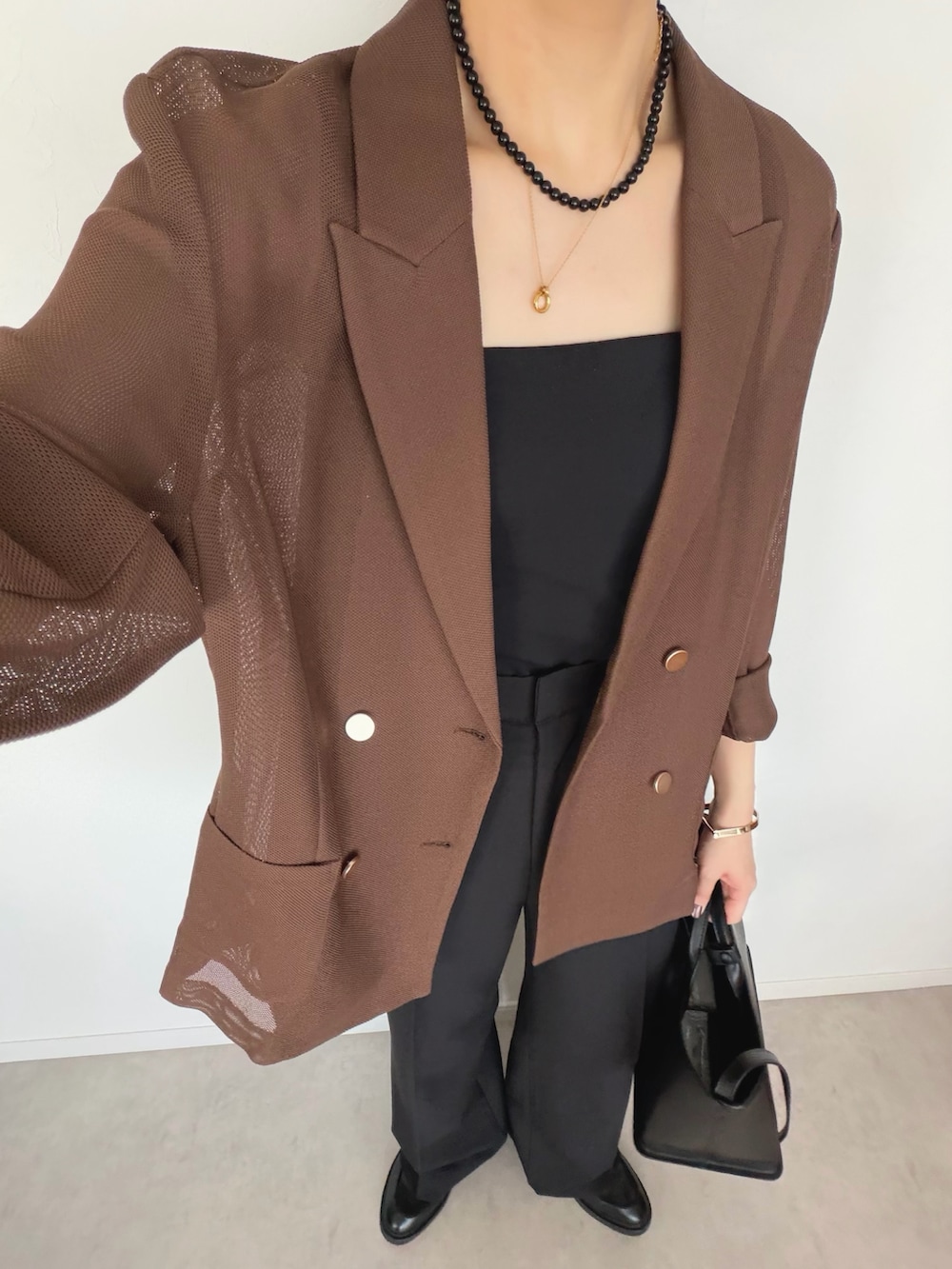 ブラウン系のテーラードジャケット、ブラック系のスラックス、ブラック系のトートバッグを着用したレディースの春コーディネートの4枚目の写真