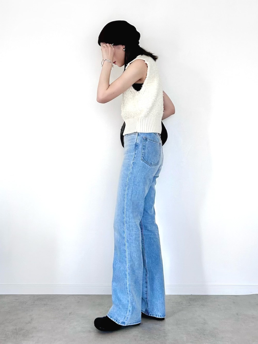 ブルー系のデニムパンツ、ホワイト系のベスト、ブラック系のショルダーバッグを着用したレディースの夏コーディネートの3枚目の写真