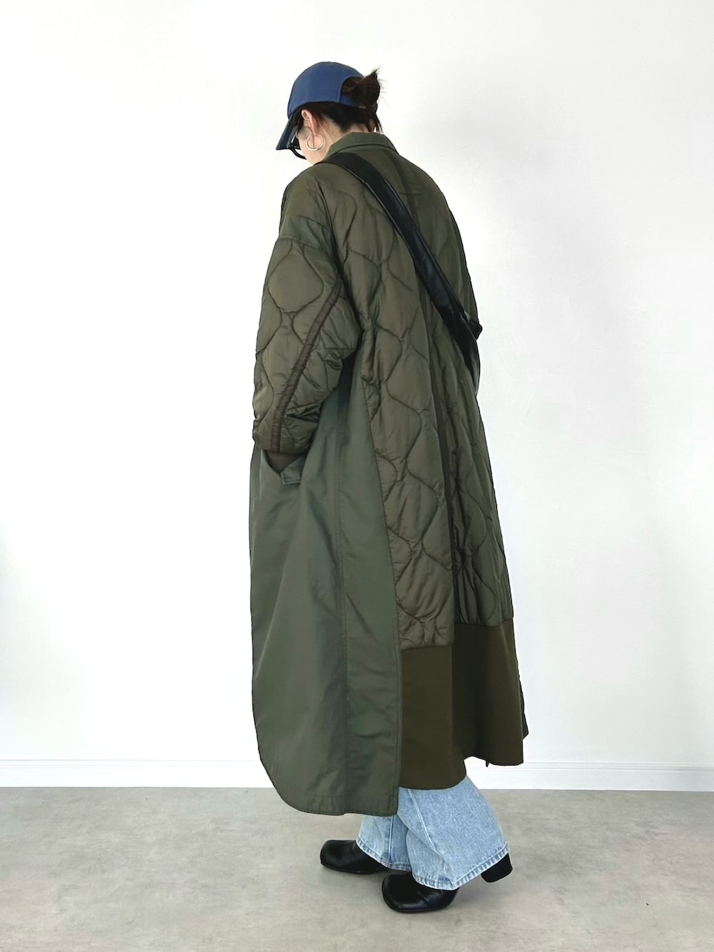 グリーン系のモッズコート、グレー系のニット/セーター、ブラック系のショルダーバッグを着用したレディースの冬コーディネートの2枚目の写真