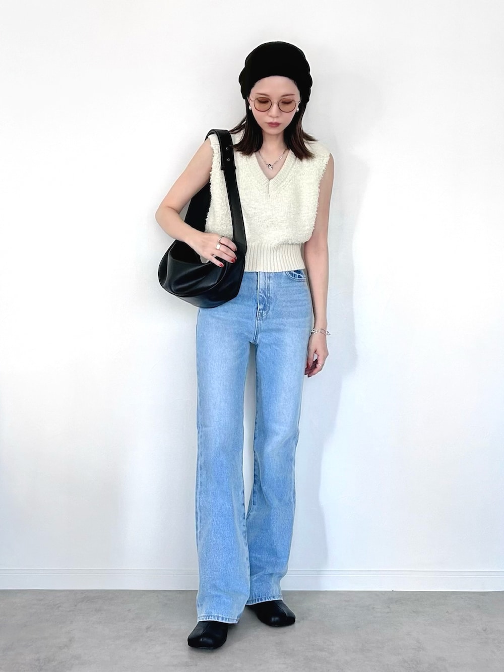 ブルー系のデニムパンツ、ホワイト系のベスト、ブラック系のショルダーバッグを着用したレディースの夏コーディネートの2枚目の写真