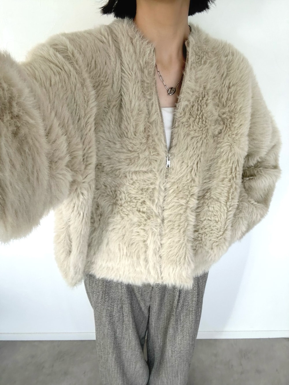 ホワイト系のカーディガン/ボレロ、ベージュ系のパンツ、ブラック系のトートバッグを着用したレディースの秋コーディネートの2枚目の写真