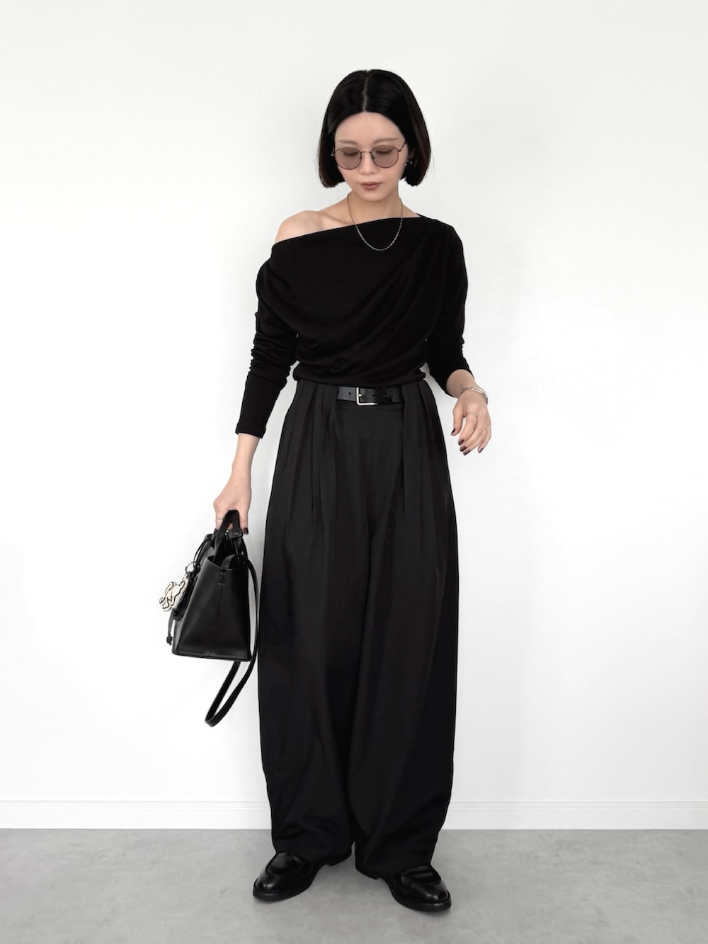 ブラック系のスラックス、ブラック系のTシャツ/カットソー、ブラック系のトートバッグを着用したレディースの春コーディネートの2枚目の写真