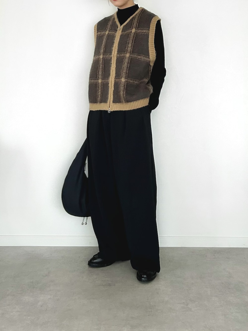 ブラウン系のベスト、ブラック系のニット/セーター、ブラウン系のブルゾンを着用したレディースの冬コーディネートの2枚目の写真