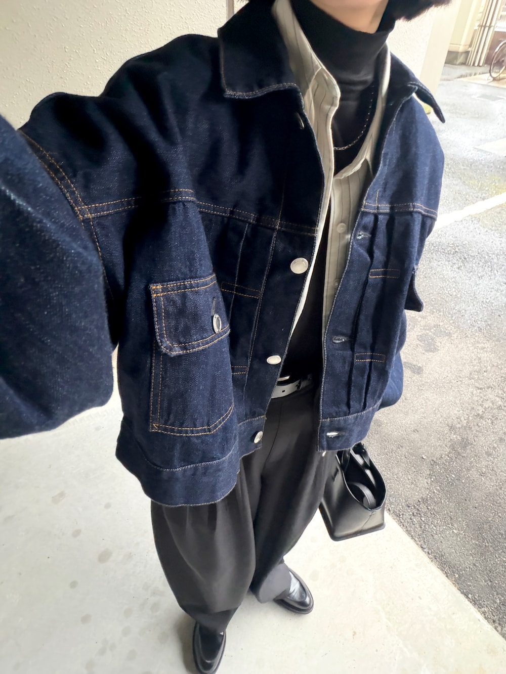 ブラック系のスラックス、ブラック系のトートバッグ、ベージュ系のシャツ/ブラウスを着用したレディースの春コーディネートの2枚目の写真