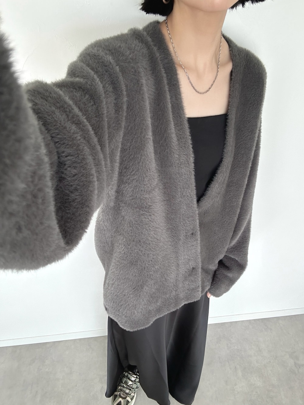 グレー系のカーディガン/ボレロ、ブラック系のショルダーバッグ、ブラック系のスカートを着用したレディースの秋コーディネートの2枚目の写真