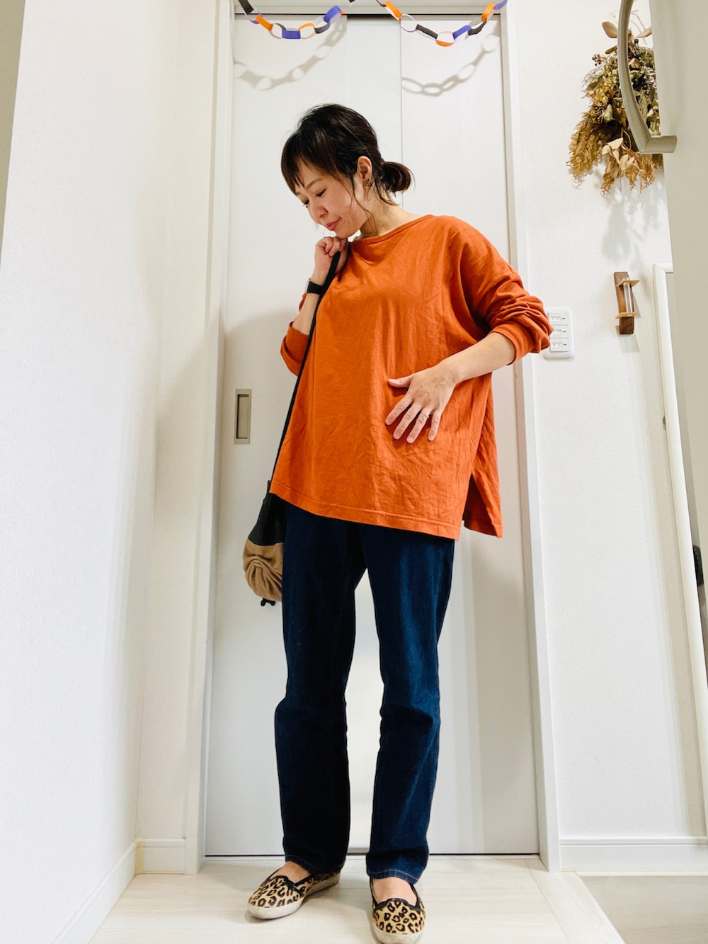 ブルー系のデニムパンツ、オレンジ系のTシャツ/カットソー、レッド系のショルダーバッグを着用したレディースの秋コーディネートの3枚目の写真