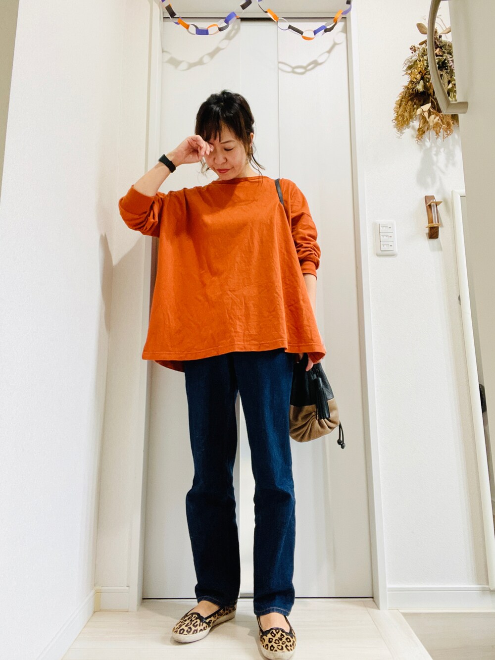 ブルー系のデニムパンツ、オレンジ系のTシャツ/カットソー、レッド系のショルダーバッグを着用したレディースの秋コーディネートの2枚目の写真