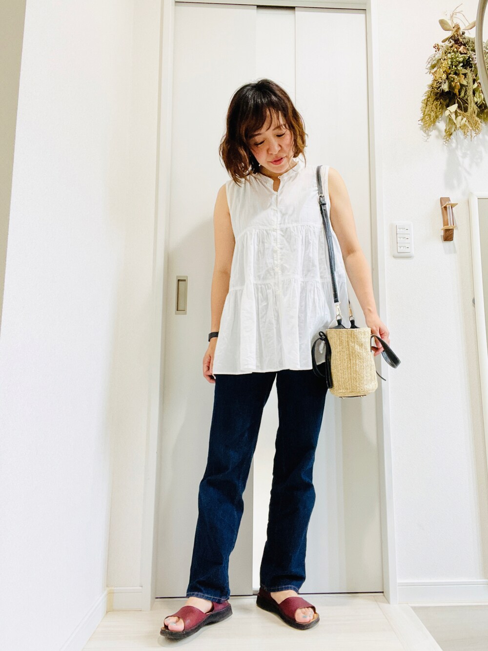 ブルー系のデニムパンツ、ブラック系のかごバッグ、レッド系のサンダルを着用したレディースの夏コーディネートの2枚目の写真