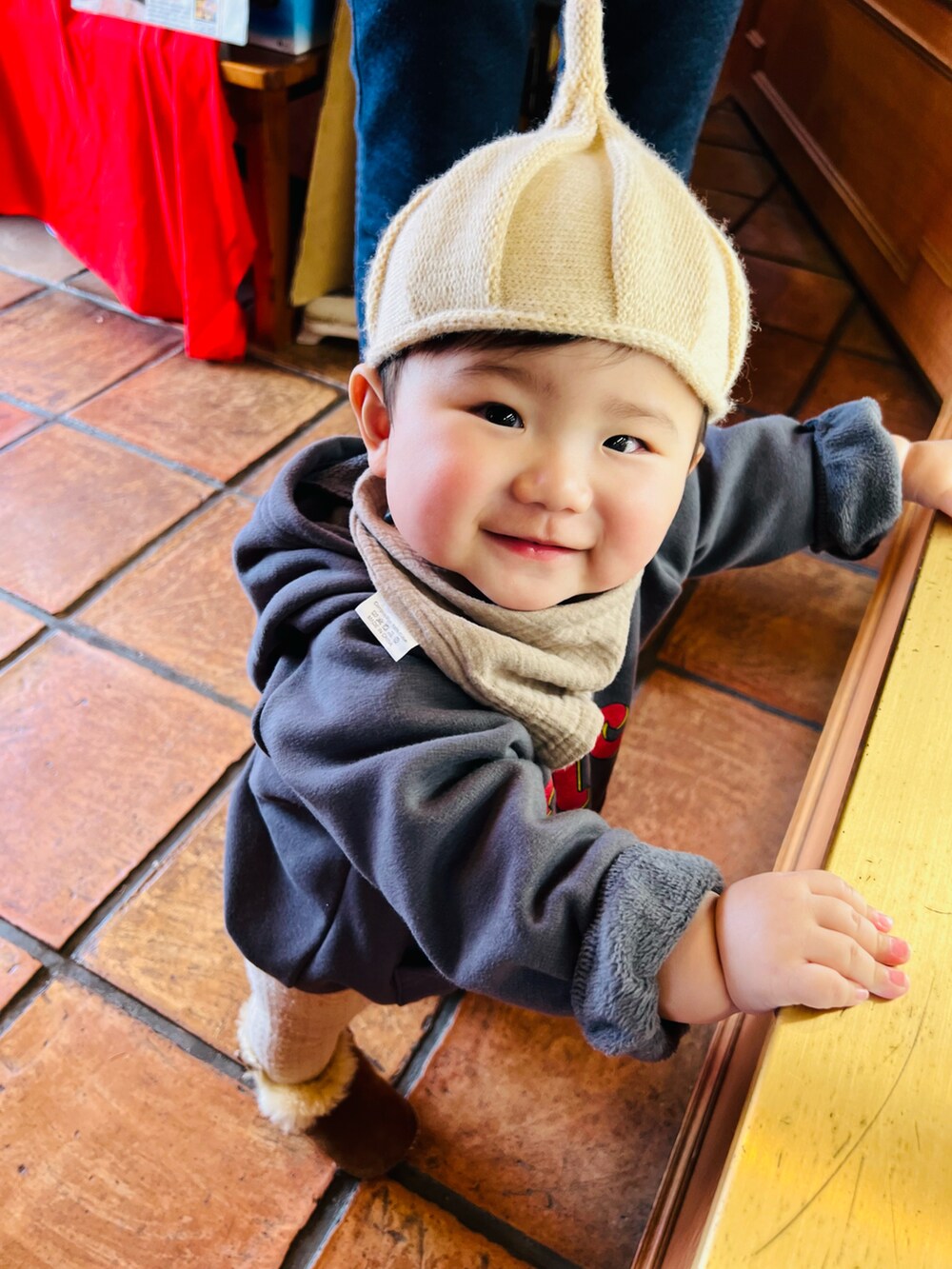 ベージュ系の帽子、ブラウン系のスタイ/よだれかけ、グレー系のその他ベビーウェアを着用したキッズの冬コーディネートの3枚目の写真