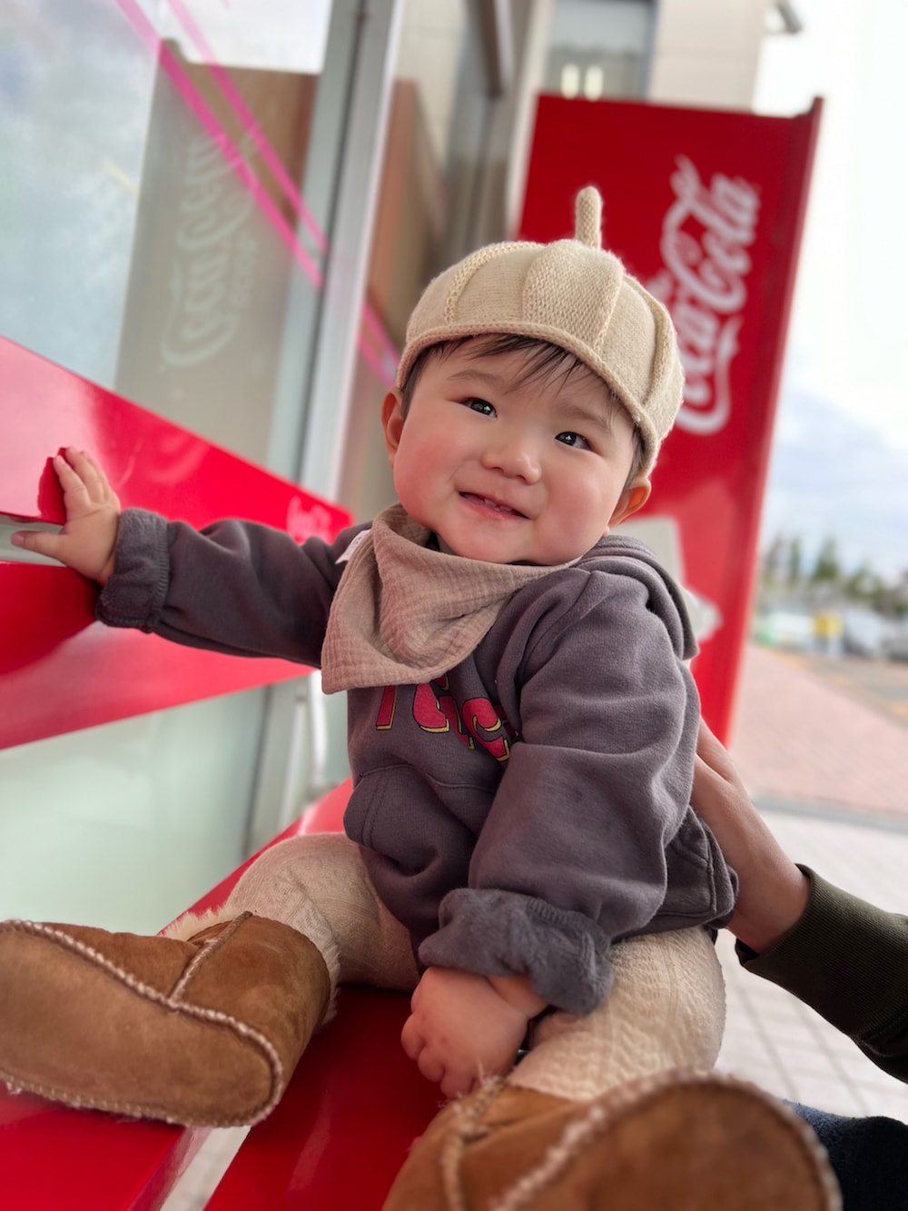 ベージュ系の帽子、ブラウン系のスタイ/よだれかけ、グレー系のその他ベビーウェアを着用したキッズの冬コーディネートの2枚目の写真